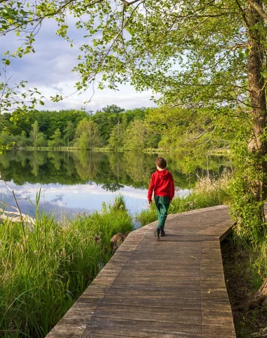 Enfant qui se promène sur les pilotis de l'ENS de la Save à Arandon-Passins (Balcons du Dauphiné) pendant une balade facile à pied